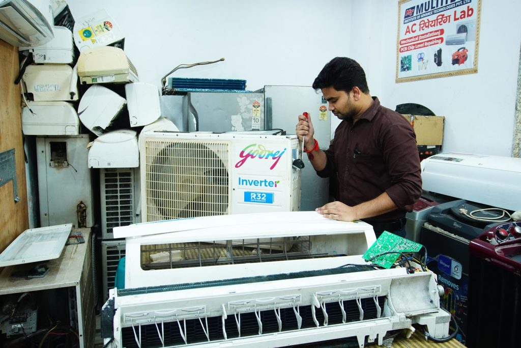 AC technician repairing the indoor unit of a split air conditioner on a workbench