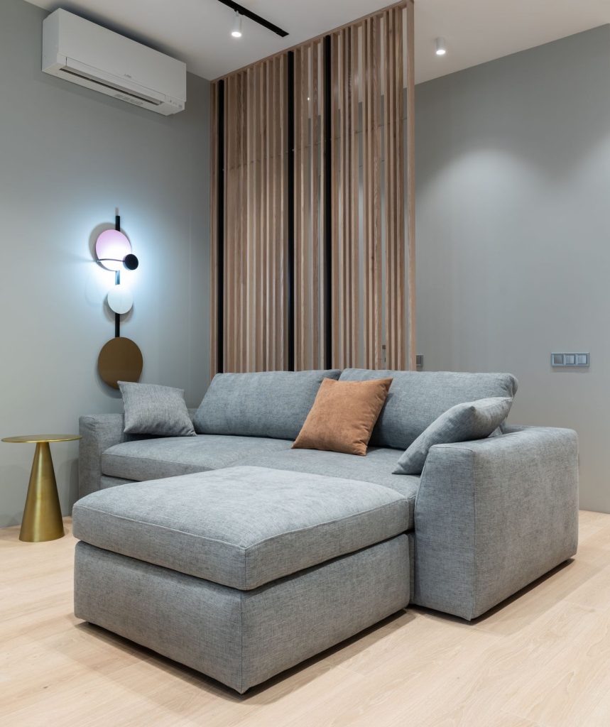 Modern living room with a sofa and round table under a wall-mounted air conditioner