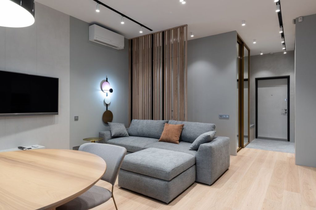 Bright modern living room with a grey sofa and a wall-mounted air conditioner