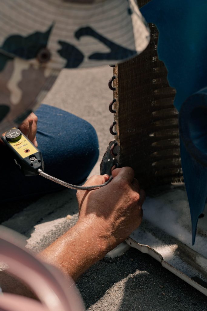 Technician repairing an air conditioner unit with hand tools
