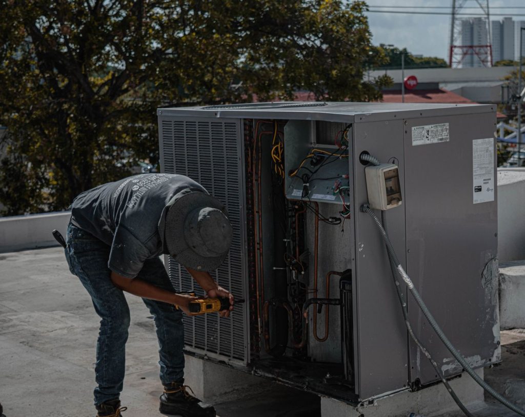 Technician repairing an air conditioning unit on a rooftop